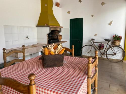 uma cozinha com uma mesa com lareira e uma bicicleta em Quinta dos Avós em Juncal