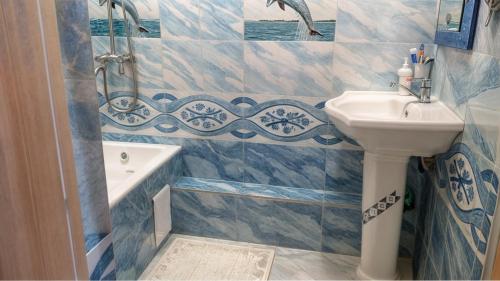 een blauw-witte badkamer met een wastafel en een badkuip. bij Квартира в тихом районе-идеально для семьи и командировки in Doesjanbe