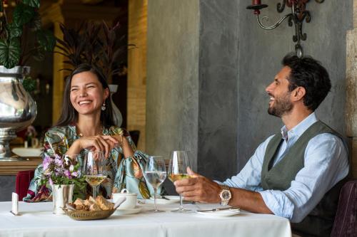 a man and woman sitting at a table with wine glasses at Gstaad Palace in Gstaad