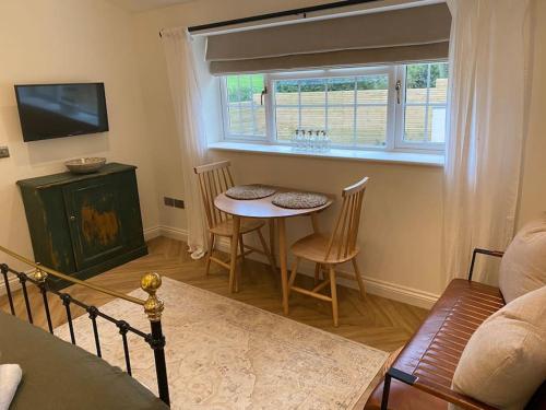 a living room with a table and a window at Stylish 1 bed studio hot tub &gym close to Lyme in Axminster