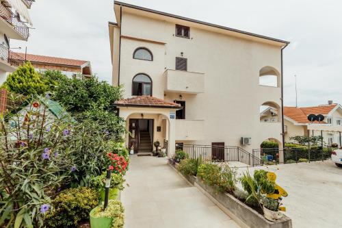 ein großes weißes Haus mit einem Innenhof mit Blumen in der Unterkunft Apartments Kosta in Tivat