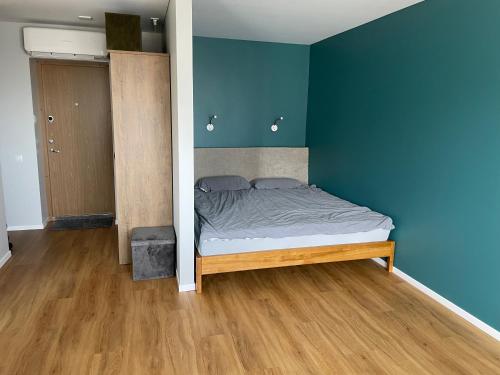 1 dormitorio con 1 cama con pared azul en Cozy Urban Retreat, en Panevėžys