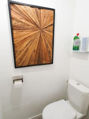 La salle de bains est pourvue de toilettes avec une photo en bois sur le mur. dans l'établissement EXIGEHOME - Magnifique T3 à 10 km de Paris Porte de St Cloud, à Vaucresson