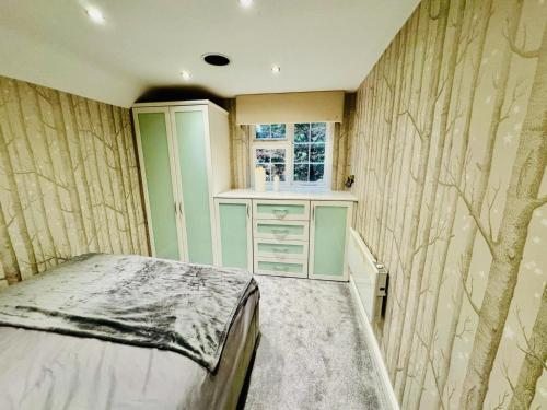 a bedroom with a bed and a tree patterned wall at Meadow View Haven in Theydon Bois