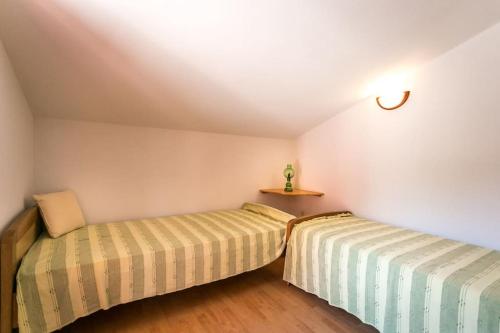 two beds in a room with white walls and wooden floors at Apartment Beach Stara Porozina in Porozina