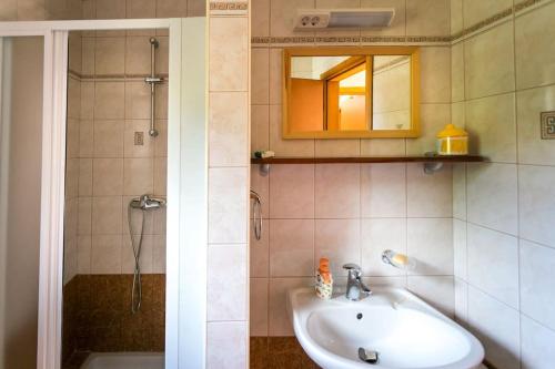 een badkamer met een wastafel en een douche met een spiegel bij Apartment Beach Stara Porozina in Porozina