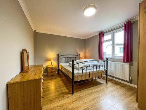 a bedroom with a bed and a window with red curtains at 5 Berth Dog Friendly Lodge In Hunstanton By The Beach Ref 13015rn in Hunstanton