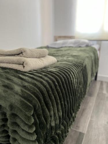 ein Bett mit einer grünen Decke darüber in der Unterkunft Piso Universidad Alicante in San Vicente del Raspeig