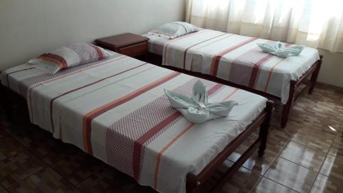 three beds in a hotel room with bows at Hospedaje Mi Bello Horizonte Jaén Perú in Jaén