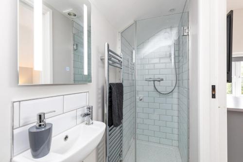 a white bathroom with a sink and a shower at The Old Bakery Angmering in Angmering