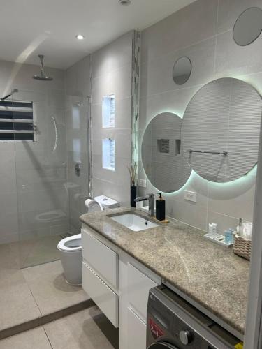a bathroom with a sink and a toilet and a mirror at Luxury Simpson bay condo in Koolbaai
