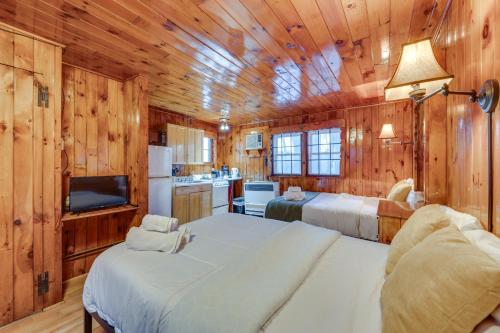 a bedroom with two beds and a kitchen with wooden walls at Cozy Laconia Studio with Pool Access - 2 Mi to Lake! in Laconia