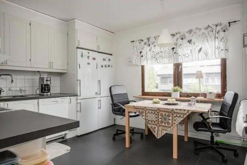 a kitchen with white cabinets and a table and chairs at Karlstad Unic House kronoparken in Karlstad