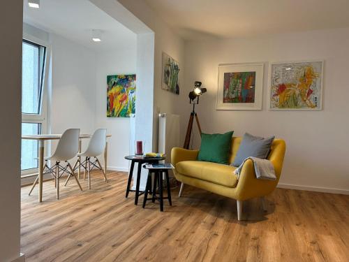 a living room with a yellow couch and chairs at City Apartment mit TG Stellplatz - Glücks-Quartier Urban 01 in Pforzheim