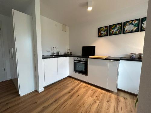 cocina con armarios blancos y suelo de madera en City Apartment mit TG Stellplatz - Glücks-Quartier Urban 01, en Pforzheim