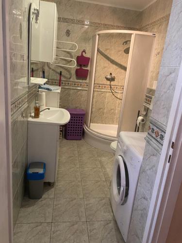 a bathroom with a shower and a sink and a washing machine at Apartament „Na wydmie” in Ustka