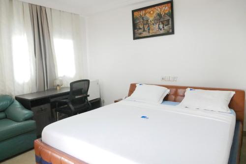 Meka Hotel في كارا: غرفة نوم بسرير ابيض ومكتب وكرسي