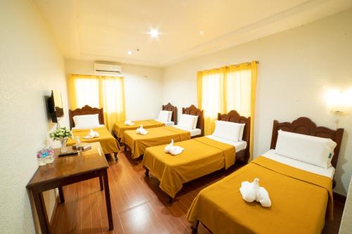 a room with four beds with yellow sheets at Casañas Suites in Puerto Princesa City