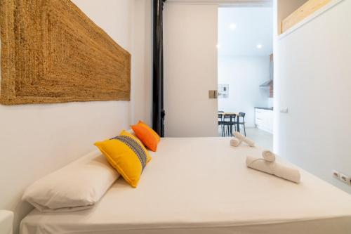 a bedroom with a white bed with yellow and orange pillows at 2 bedrooms 1 bathroom furnished - Lavapies - Modern Cozy - MintyStay in Madrid
