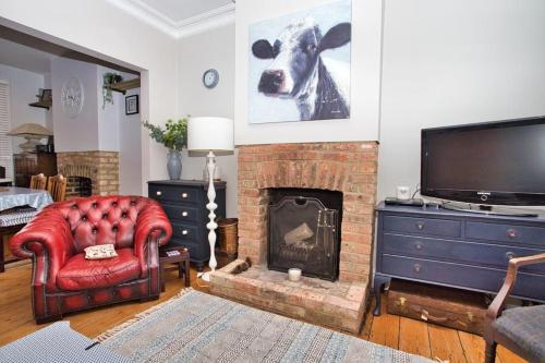 a living room with a fireplace with a cow picture on the wall at Restful and Cosy 4 Bed Home Minutes from the Beach in Kent