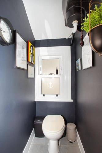 a bathroom with a toilet and a clock on the wall at Restful and Cosy 4 Bed Home Minutes from the Beach in Kent