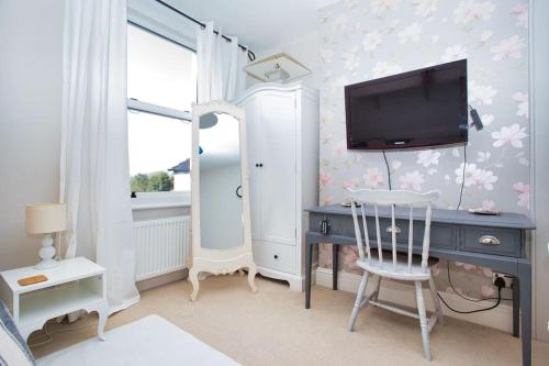 a bedroom with a desk with a tv and a chair at Restful and Cosy 4 Bed Home Minutes from the Beach in Kent
