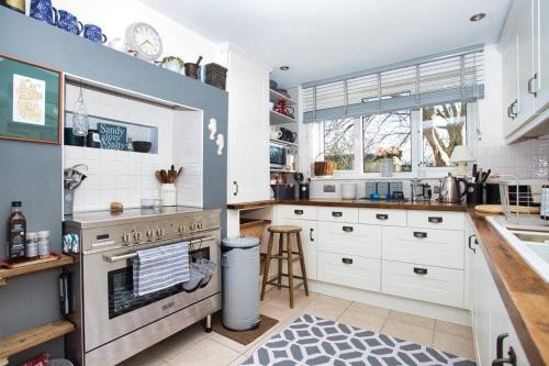 a kitchen with white cabinets and a stove and a sink at Restful and Cosy 4 Bed Home Minutes from the Beach in Kent