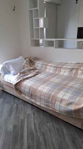 1 cama no hecha en un dormitorio con suelo de madera en Airport.24/24, en Chişinău