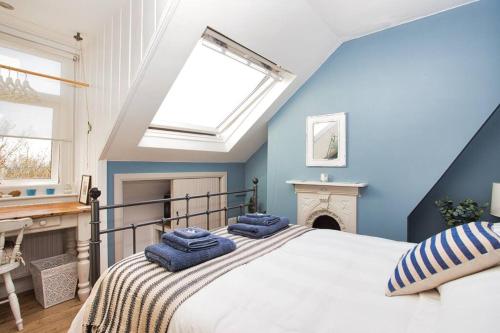 a bedroom with a bed with blue walls and a skylight at Restful and Cosy 4 Bed Home Minutes from the Beach in Kent