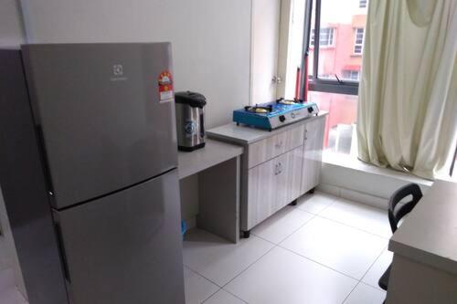 uma cozinha com um frigorífico, uma mesa e uma janela em Hotel Global Sungai Way em Kampong Baharu Sungai Way