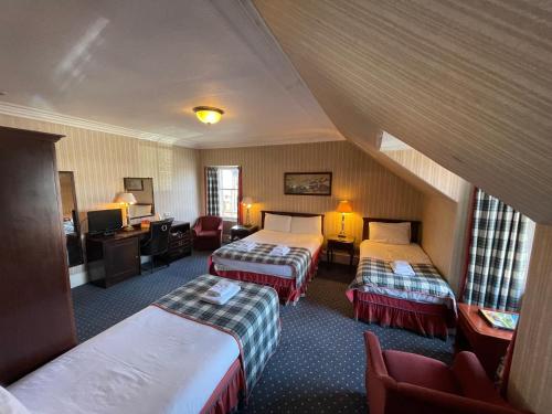 a hotel room with two beds and a desk at Lovat Arms Hotel in Beauly