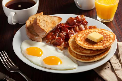 um prato de pequeno-almoço com ovos, bacon e torradas em Paradise Inn By OYO Hattiesburg North em Hattiesburg