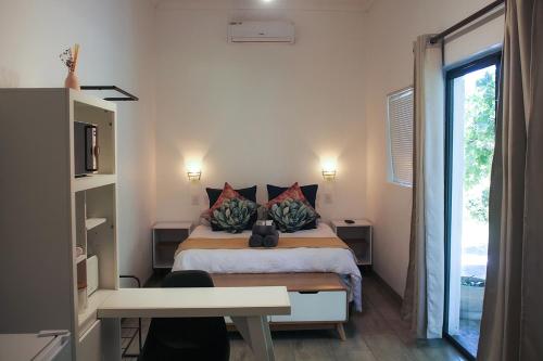 Schlafzimmer mit einem Bett, einem Schreibtisch und einem Fenster in der Unterkunft Bezalel Wine & Brandy Estate in Kanoneiland
