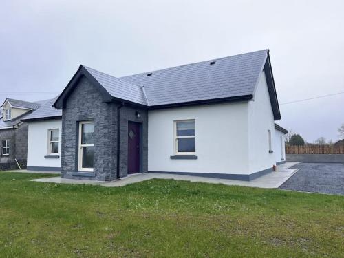 a white house with a black roof at New Atherny Home overlooking The fields of Athenry in Galway