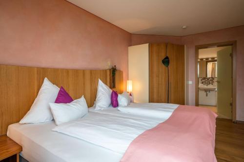 ein Schlafzimmer mit einem großen weißen Bett mit lila Kissen in der Unterkunft Ferienwohnung Rosengarten in Bad Endorf