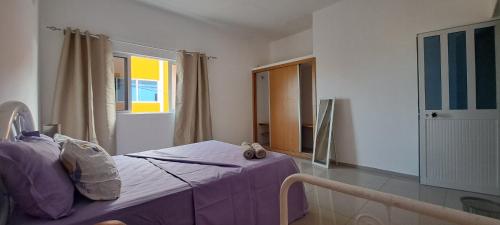 a bedroom with a bed with purple sheets and a window at Homestay Maio Apartment in Vila do Maio