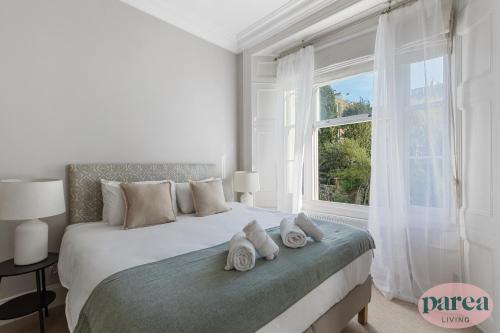 a white bedroom with a large bed with towels on it at Parea Living - Notting Hill, Stylish 1-Bedroom Flat, Private Gardens, Remote Working in London