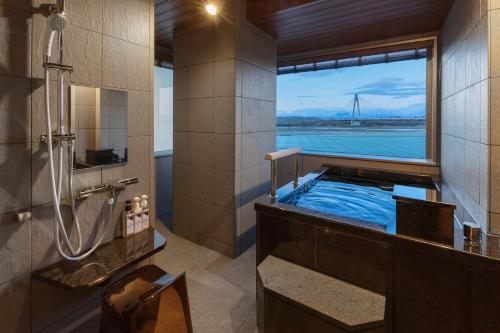 a bathroom with a tub with a view of a bridge at Tokachigawa Onsen Daiichi Hotel in Otofuke