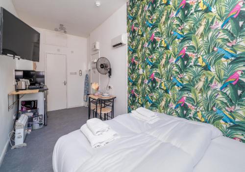 a bedroom with a white bed with a tropical wallpaper at Private Studio Unit in Chapel Market London in London