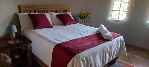 1 dormitorio con 1 cama grande con sábanas rojas y blancas en Kolobeng Valley en Ranku