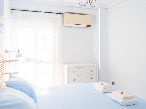 a white bedroom with a bed with towels on it at Riverside Apartment in Triana in Seville