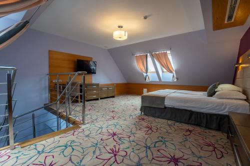 a hotel room with a bed and a staircase at Hotel & SPA Czarny Groń in Rzyki
