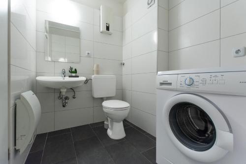 y baño con lavamanos y lavadora. en T&K Apartments - 3 Room Apartment with Balcony, en Essen