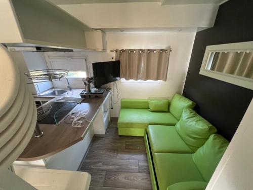una pequeña cocina con asientos verdes en una casa pequeña en Mobil Home confort 6p, en Cadenet