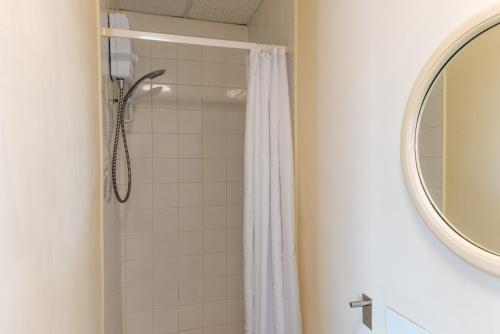 a shower with a white shower curtain and a mirror at Superior Sea View Apartment 8 in Plymouth