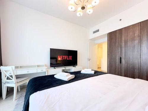 1 dormitorio con 1 cama blanca grande y TV de pantalla plana en Dar Vacation - Bright and Charming 1 BR Apartment, en Dubái