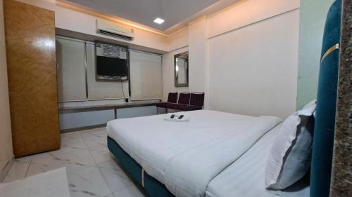 a bedroom with a large white bed and a window at Hotel Lokhandwala residency in Mumbai