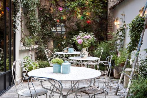 - deux tables et des chaises sur une terrasse fleurie dans l'établissement Hôtel Henriette, à Paris