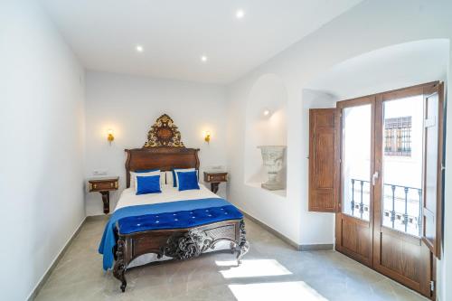 a bedroom with a large bed with blue pillows at CASA DE LA SEÑORA in Palma del Río