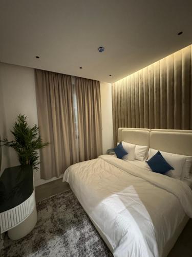 ein Schlafzimmer mit einem großen weißen Bett mit blauen Kissen in der Unterkunft غرفة وصالة بتصميم فندقي in Riad